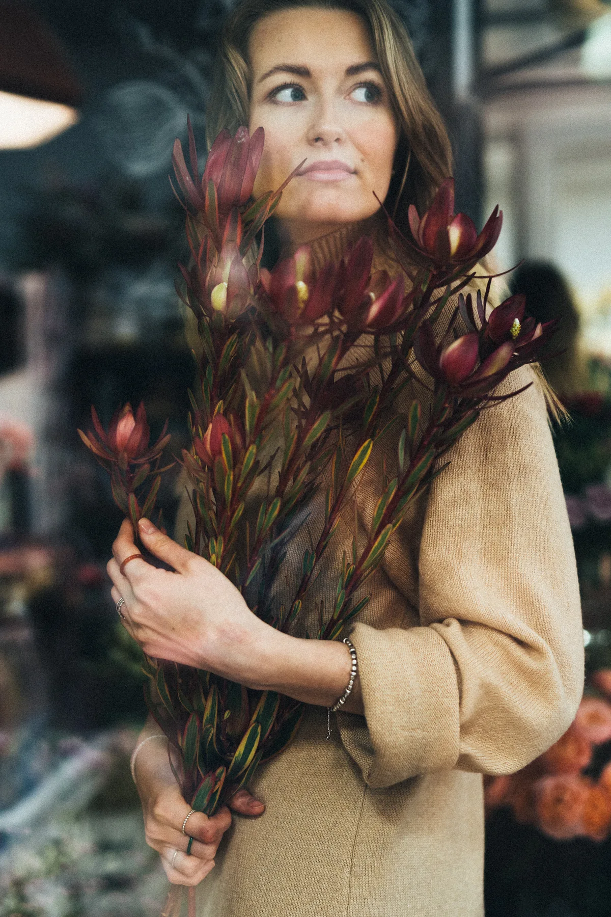 Portrait of a woman holding branches, seen through reflective glass.