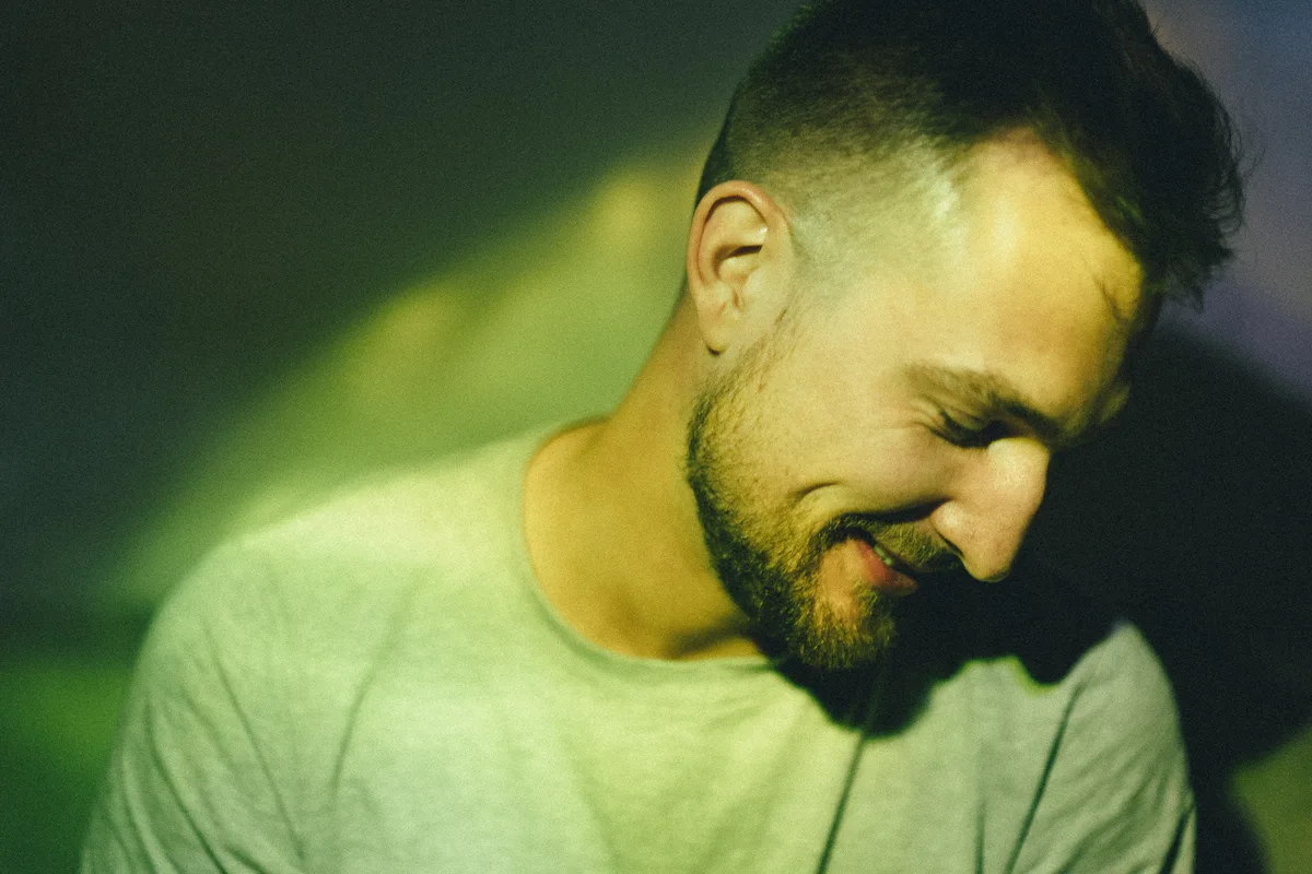 A smiling man with a band of green-yellow light across his face.