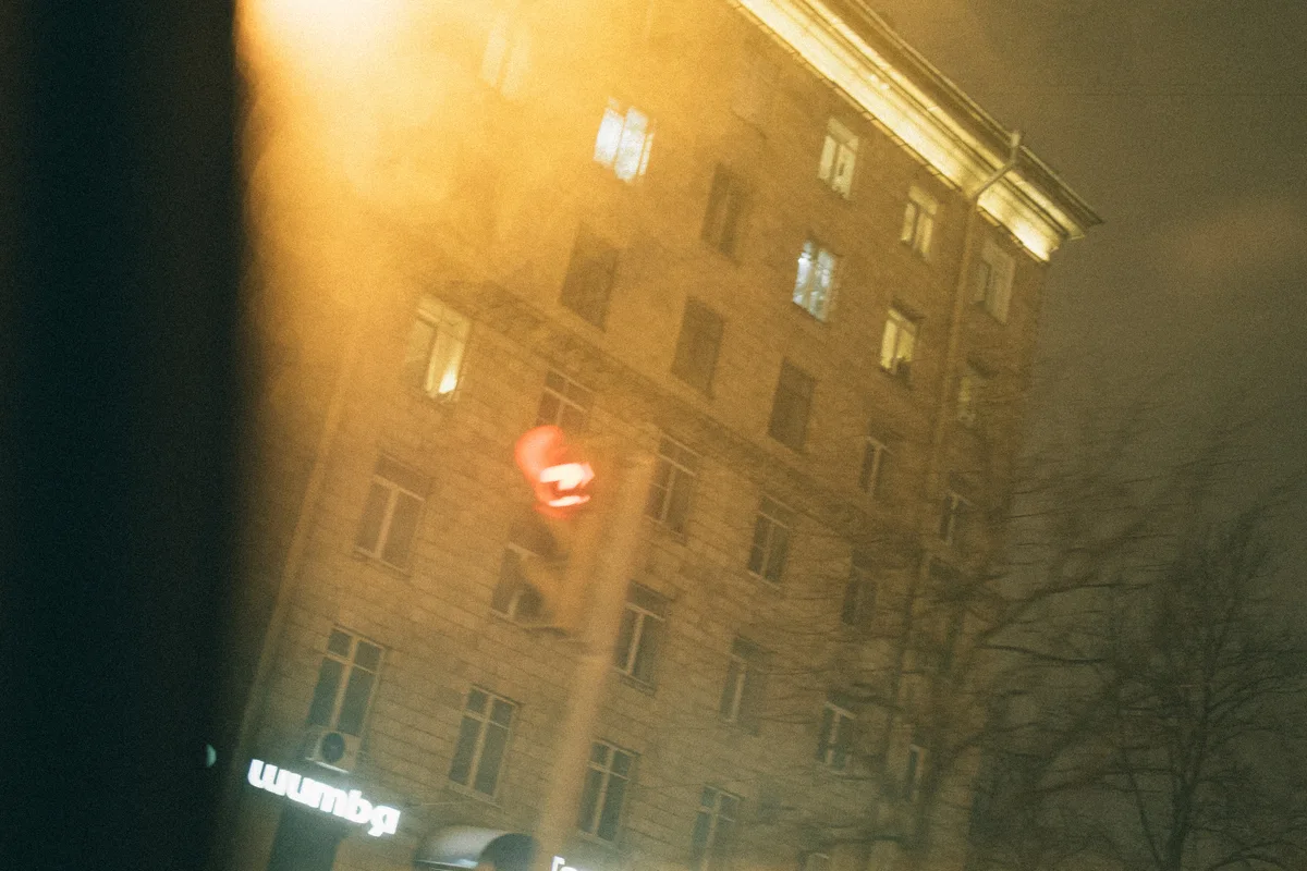 A building and traffic light seen through glowing, blurred glass at night.