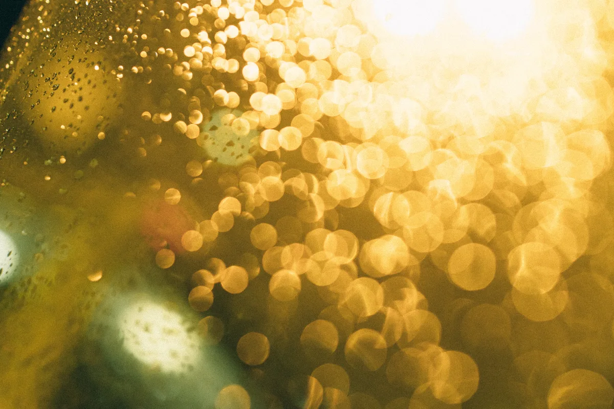 Golden circles of light seen through water droplets on glass.