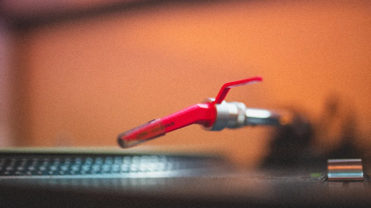 Close view of a red record-player cartridge above a vinyl record.