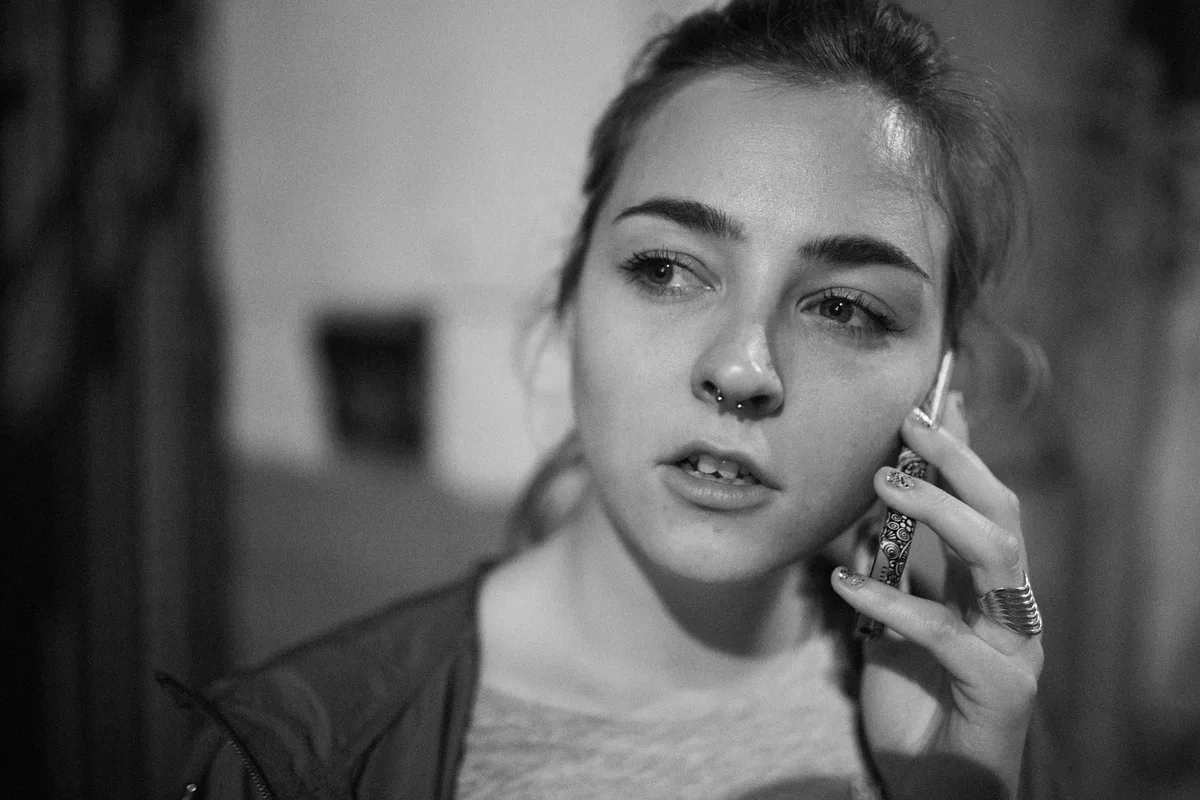 Black-and-white close portrait of a woman holding a phone.