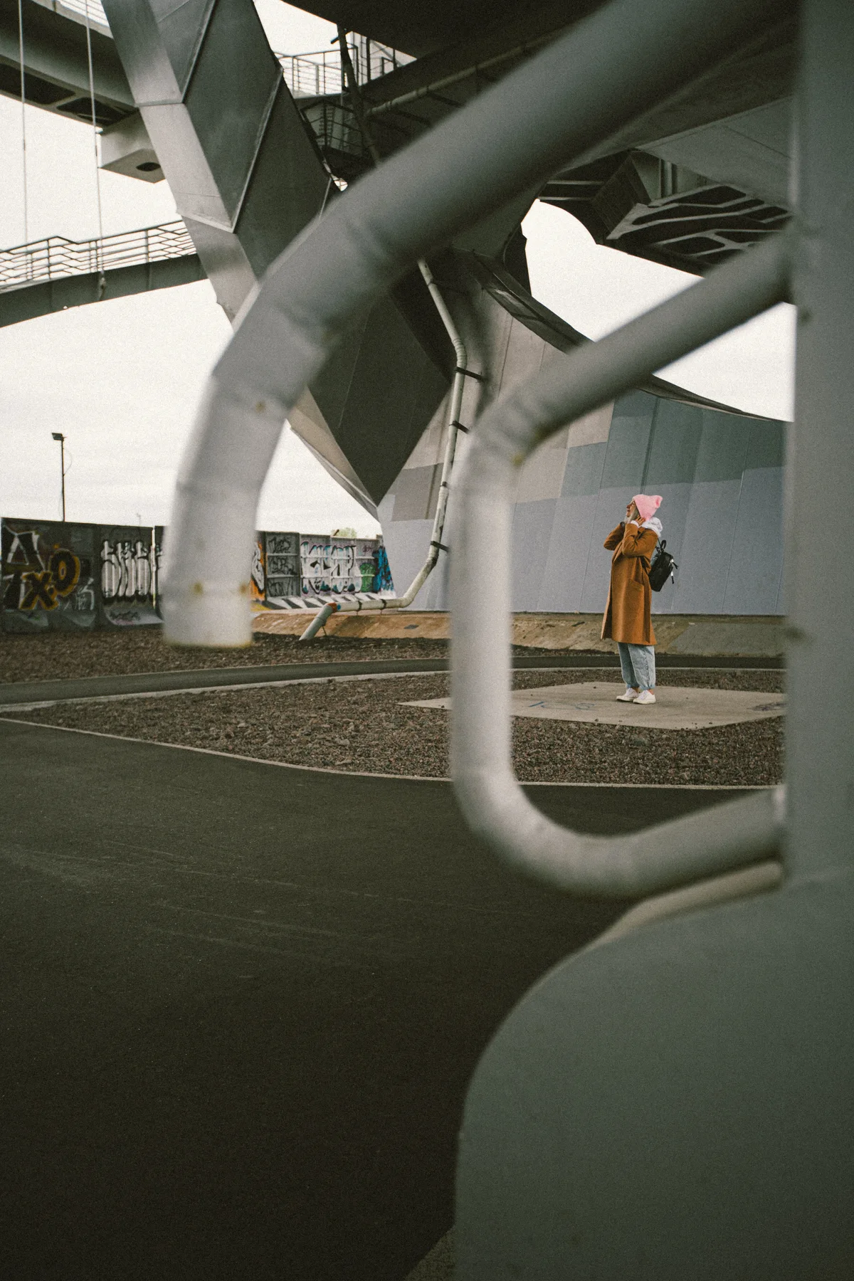 A person standing among large pale structural supports.