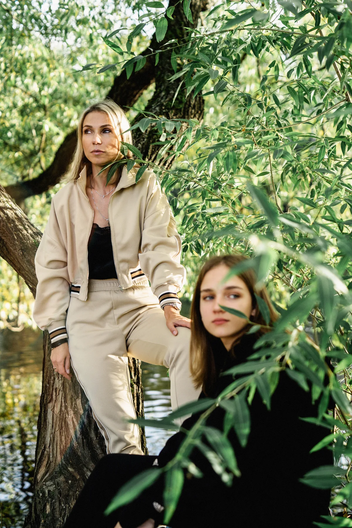 Two women posed at different heights amid dense foliage.