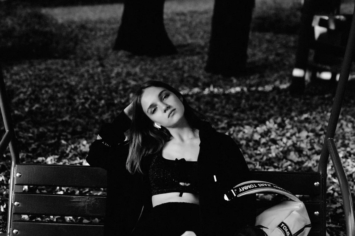 Black-and-white portrait of a woman seated on a park bench.