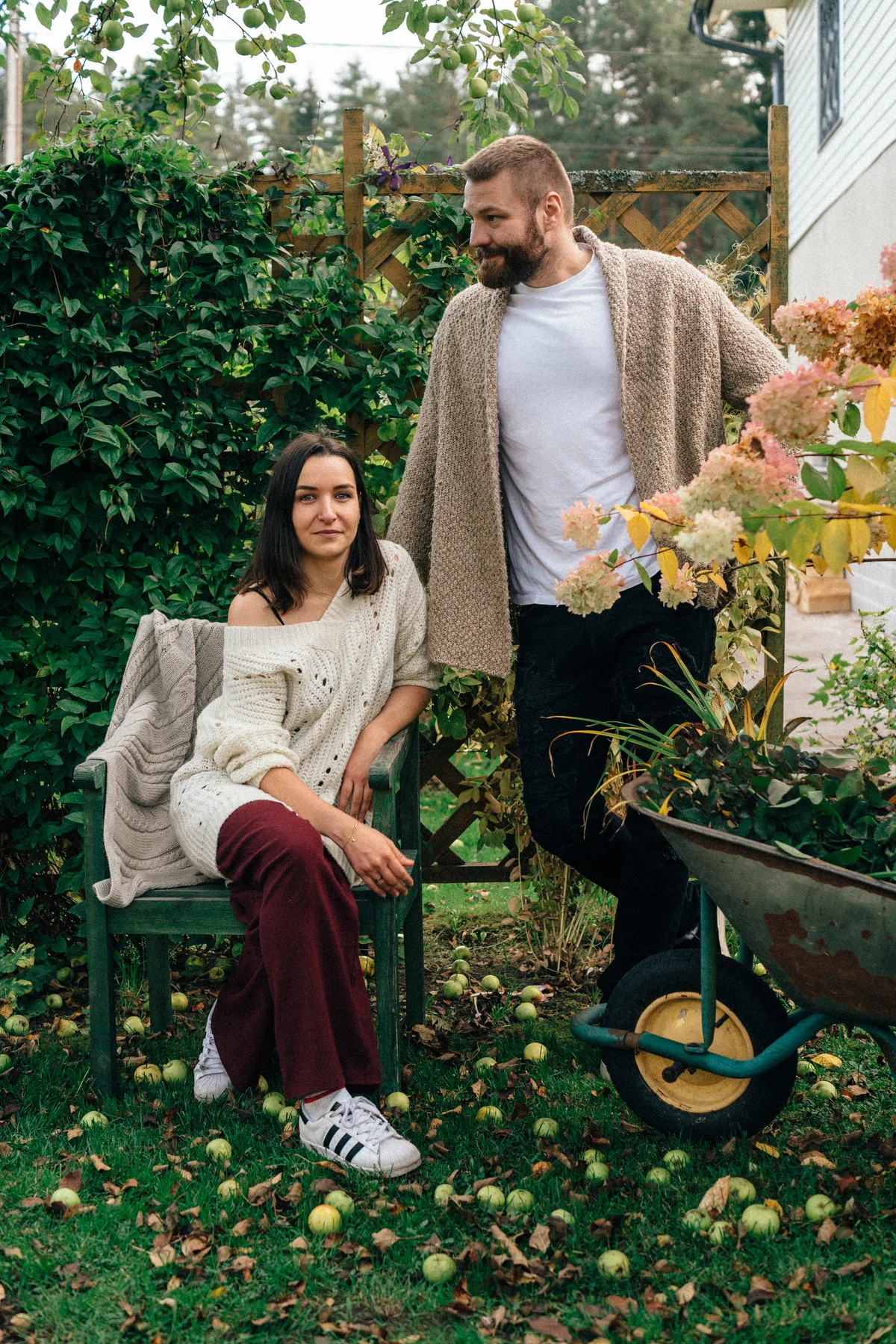 Two adults and a child beside a garden path and flowering plants.