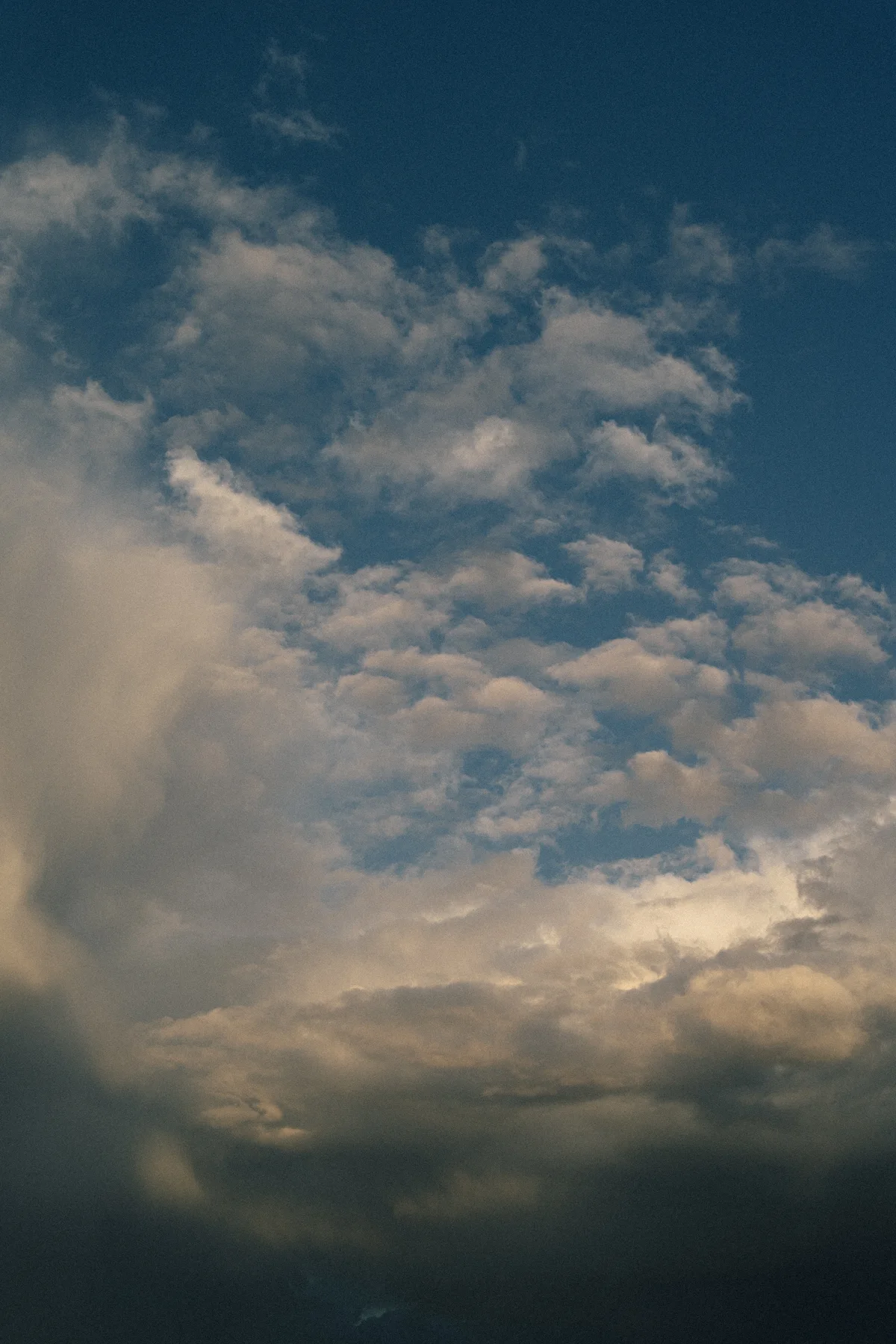 Layered clouds in a blue sky, lit warmly from below.
