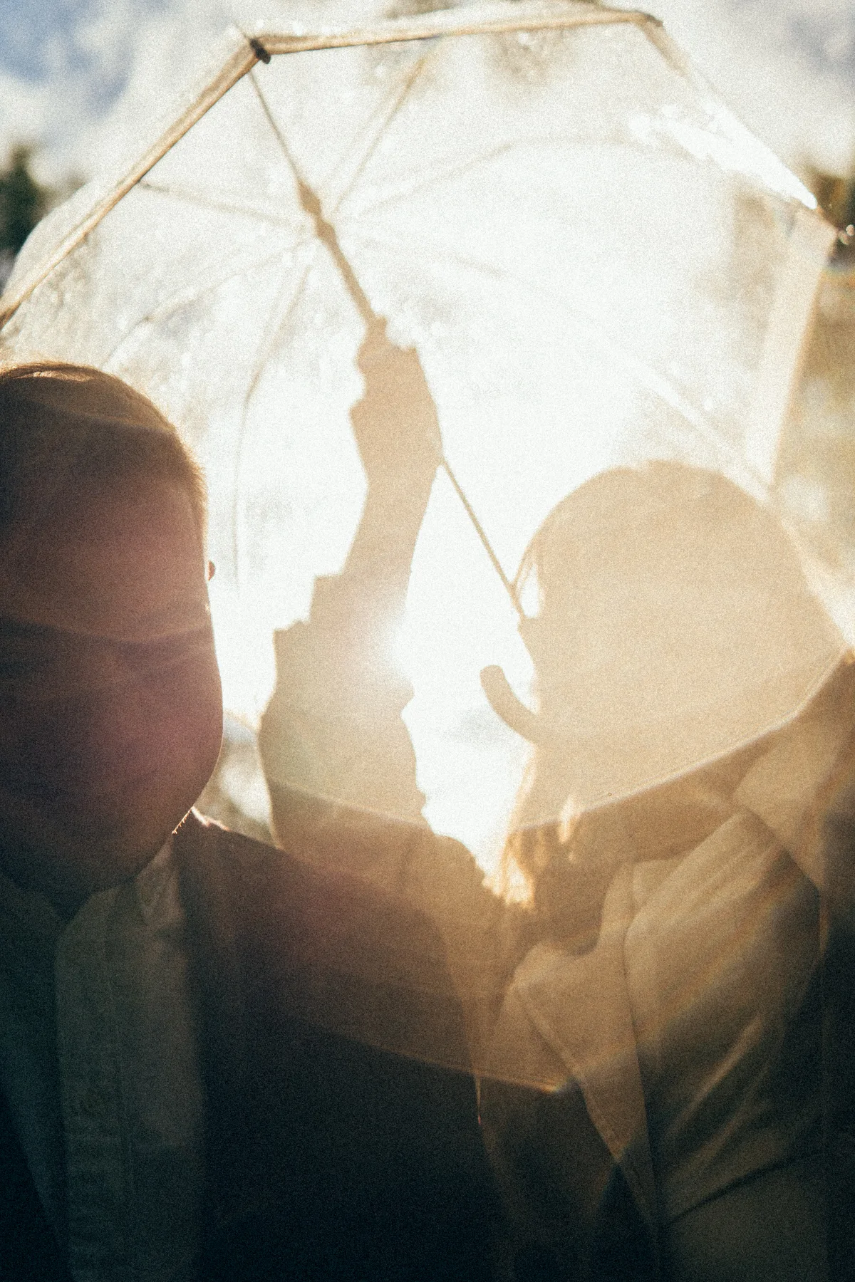 A face partly hidden by bright leaves and translucent reflections.