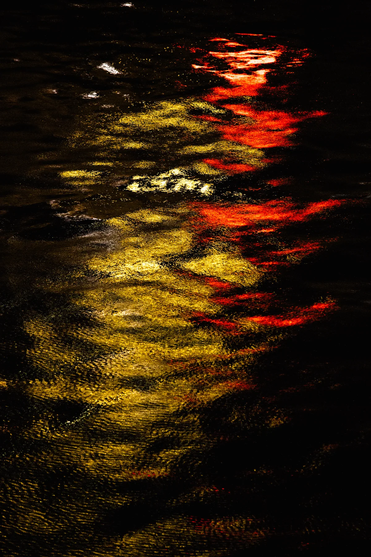 Red and yellow reflections ripple across dark water.