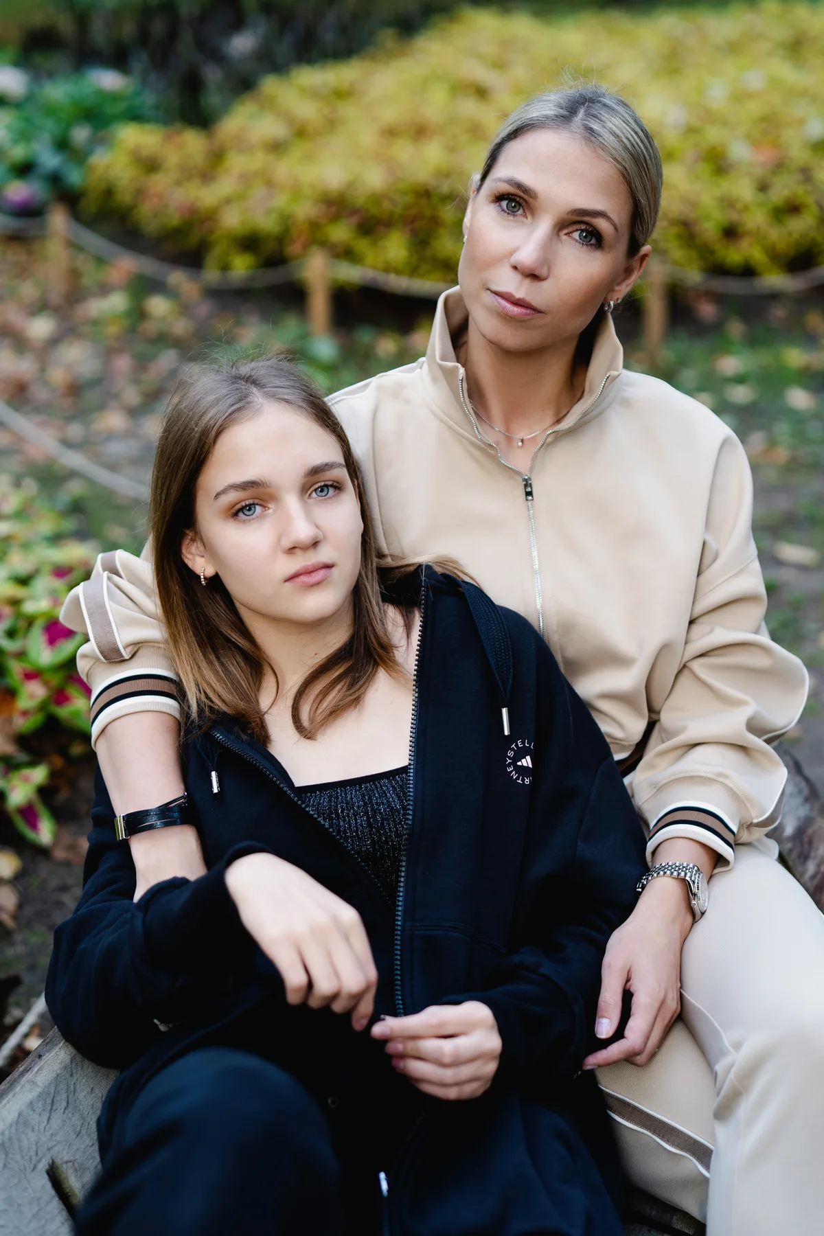 Two women seated close together among greenery.