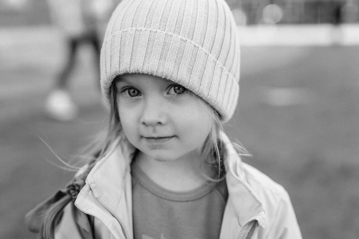 Black-and-white close portrait of a child in a knitted hat.