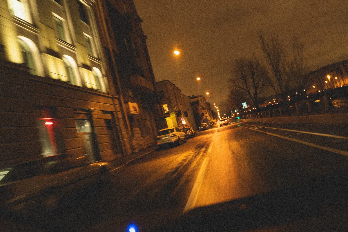 Warm street lights stretch across a night road in motion.